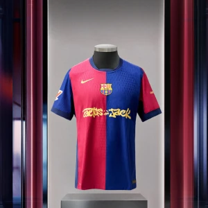 FC Barcelona x Travis Scott Home Jersey (fan edition) - Säljer en FC Barcelona x Travis Scott matchtröja i röd och blå med klubbmärke på bröstet och Nike-logga i guld. Tröjan har korta ärmar och är tillverkad i ett lätt, ventilerande material. Unik design med Travis Scott-grafik på framsidan.