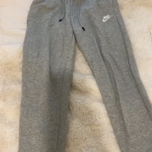 Grå mjukisbyxor från Nike - Grå mjukisbyxor från Nike med dragsko i midjan och vit Nike-logga på höger höft. Priset kan diskuteras 