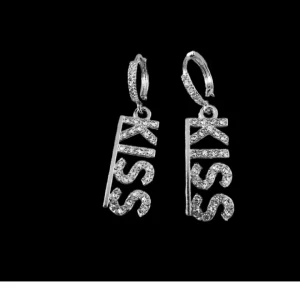 Glittriga örhängen med texten KISS - Säljer ett par coola örhängen i silverfärg med gnistrande stenar och texten 'KISS'. Perfekta för dig som vill sticka ut och addera lite edge till din look. Hängande modell med snygg detalj.