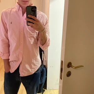 Ralph Lauren skjorta - Säljer en riktigt sommrig ljusrosa skjorta från Ralph Lauren med button down-krage. Storlek 18 (S) in modellen custom fit