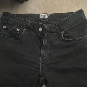 Svarta jeansbyxor från 157 - Svarta jeansbyxor från 157 i storlek M med kort längd. Klassisk ficksmodell med dragkedja och knapp framtill samt fickor med lock och knapp bak. Perfekta för dig som gillar en enkel och stilren look. Är även straight och mid rise.