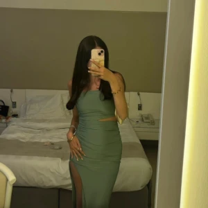 Grön långklänning med slits och cut-out - Snygg grön långklänning med tight passform, högt slits på ena benet och cut-out detalj vid midjan. Klänningen har ärmlös design och raka linjer upptill. Väldigt stretchig så den kan passa storlek S också😊 Ni kan skriva om ni vill se tydligare bilder för dom klipps på Plick! Pris kan diskuteras vid snabb affär