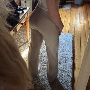 Beiga kostymbyxor med normal passform - Snygga beiga kostymbyxor med raka ben och normal midja. Byxorna har klassiska fickor fram och stängs med dragkedja och hake. Perfekta för en stilren look och passar till många olika outfits.