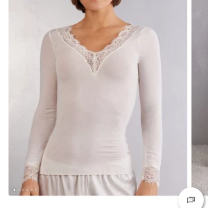 Vit intimissimi tröja - Säljer en elegant vit långärmad topp med v-ringning och fina spetsdetaljer, den är bara använd 2 ggr och är i inprincip nytt skick, skriv om du vill ha fler bilder på tröjan💕