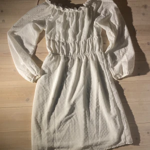 Vit offshoulder klänning från H&M Divided - Söt vit klänning från H&M Divided i storlek XS. Klänningen har offshoulder-modell, långa puffärmar och resår i midjan. Tunt, lätt material med diskret prickigt mönster. Perfekt för sommarens alla tillfällen!
