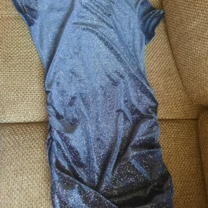 Glittrig marinblå klänning - Gabska tight passform, materialet är mjukt och stretchigt, men det är inte en somrig klänning, då tyget är ganska varmt, jag skulle använda den mer på jul eller nyår till exempel. Köpt på second hand så nypris 70 kr, lappen är avklippt så vet ej vart den är från!