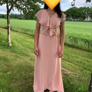 Ljusrosa långklänning från Vero Moda - Använd endast en gång. Mycket fint skick!  Anpassningsbar i midjan (knyter i midjan).  ”Jag” på bilden: 157cm lång