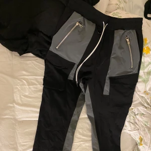 Svart & grå byxor helt nya med lapp kvar - Säljer ett par svarta  byxor med gråa detaljer och fickor med dragkedja plus vanliga fickor. Helt nya aldrig använt dom bara testat dom men passade inte mig tyvärr.  Priset kan diskuteras bara hör av dig 