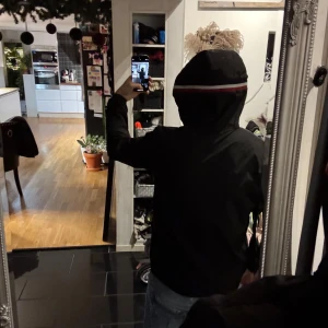 Svart jacka från Moncler (Windbreaker) - Säljer en stilren svart jacka från Moncler med huva och dragkedja. Jackan har en broderad logotyp på ärmen och en röd-vit randdetalj på huvan. Perfekt för kyligare dagar. Nfc Scan! Cond är 8/10 då jag bara använt den under hösten men är sugen på något annat. För mer frågor skriv gärna till mig och pris kan gå ner vid smidigt köp. (Snören har lossnat). De vita prickarna på bilden är endast damm i luften