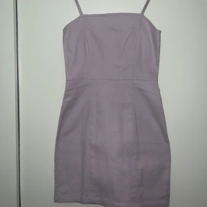Ljuslila kort klänning med smala axelband - Säljer en söt ljuslila klänning med smala axelband och figurnära passform. Klänningen har dragkedja i ryggen och är ärmlös, perfekt för varma dagar eller sommarens tillfällen. Aldrig använd. 
