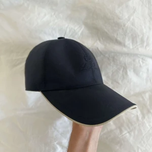 Mörkblå keps - Loro Piana - Mörkblå keps från Loro Piano. Köpt i London och använd i runt 6 månader. Storlek: M. Skick: 8/10. Hör av er om ni är intresserade!🙌