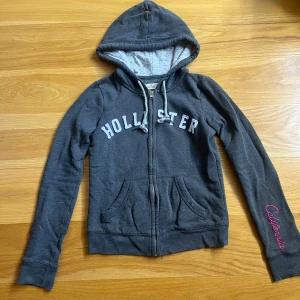 Mörkgrå hoodie med dragkedja från Hollister - Mysig mörkgrå hoodie från Hollister!