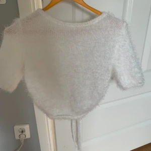 Vit fluffig stickad topp från NA-KD x Hanna Schönberg - Jättefin fluffig topp med öppen rygg från NAKD från Hanna schöbergs kollektion. Säljer då den aldrig kommer till användning. Aldrig använd, pris kan diskuteras vid snabb affär.