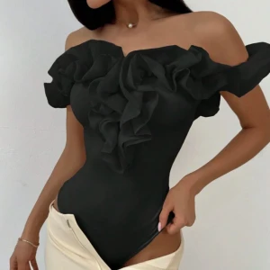 Snygg fest body! - Trendig svart offshoulder body med stora volangdetaljer framtill och runt axlarna. Toppens design är figurnära och axelbandslös, perfekt för en snygg och stilren look.