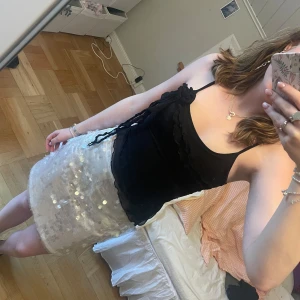 Svart volang mesh topp - Supersnygg meshtopp med volanger och en blomma! Toppen har dubbla lager så man ser inte igenom tyget även fast det är mesh:) säljer även kjolen på första bilden💞 