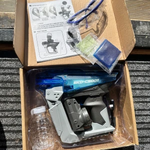 SKD Blaster CS-001 Gel Blaster - Säljer en SKD Blaster CS-001 gel blaster i originalkartong. Medföljer skyddsglasögon, instruktioner, vattenflaska och påsar med gelkulor. Blastern är grå och blå med svart handtag och har en futuristisk design. Passar för personer över 12 år.