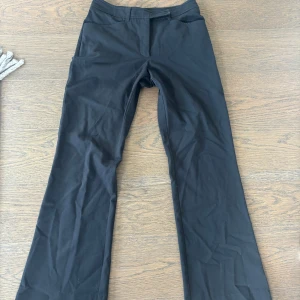 Lågmidjade kostymbyxor - Svarta lågmidjade kostymbyxor med snygg knäppning. Använda sparsmant och i fint material