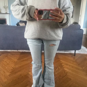 Ljusblå bootcut jeans med slitningar - Säljer ett par ljusblå jeans med bootcut passform och slitningar på båda benen. 