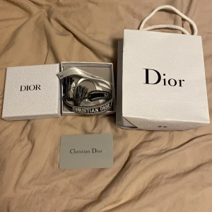 Dior armband  - Snyggt armband från Dior i svart och vitt med texten 'Christian Dior' broderad. Armbandet har en justerbar knytning och levereras i originalask och påse. Perfekt accessoar för att lyfta din stil. 