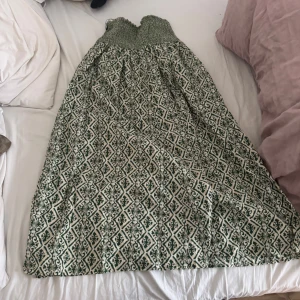 Grönmönstrad långkjol  - Säljer en långkjok i grönt  och ett snyggt grafiskt mönster. Kjolen  har en luftig passform och är perfekt för varma dagar. Superskön och stilren att bära!