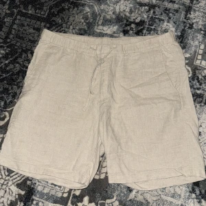 Beige linneshorts från H&M - Snygga och luftiga beige shorts från H&M i linneblandning. Modellen har normal passform, snörning i midjan och sidofickor. Perfekta för varma dagar och enkel att matcha med olika toppar.