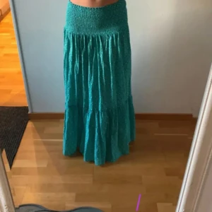 Turkos mönstrad långkjol - Säljer en jättefin turkos långkjol med diskret geometriskt mönster och smock i midjan. Kjolen har en luftig och flowy passform, säljer då den inte kommer till användning längre!