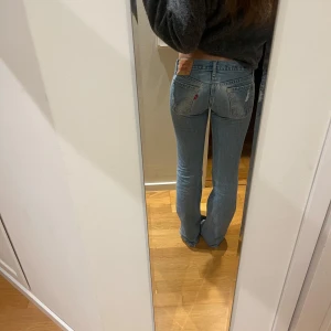 Ljusblå Levis 563 jeans - Säljer ett par klassiska ljusblå Levis  jeans med low waist bootcut modell, och normal passform. Jeansen har knappgylf och Levis ikoniska läderpatch bak i midjan.  Jag säljer dem då de blivit för tajta runt höfterna på mig. 💞💞 skriv för närmre bilder. 40 cm i midjemått, men de är låga och sitter precis på höften därför behöver de va lite bredare i midjan, till skillnad från om man har ett par högre jeans. 