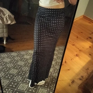 Svart långkjol med vita prickar - Säljer en svart långkjol med vita prickar. Kjolen har en rak och figurnära passform och är tillverkad i ett mjukt och följsamt material. Perfekt för dig som gillar en stilren men ändå lekfull look. Aldrig använd bara testad. Låg midja. 
