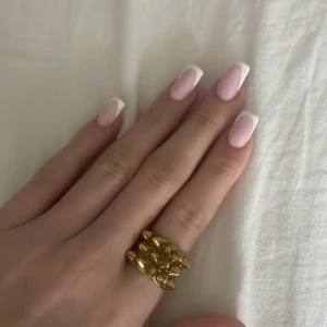 Bred guldfärgad ring med nitar - Cool och bred ring i guldfärg med markerade nitar runt om. Perfekt statement-smycke för dig som gillar att sticka ut. Ringen har en unik design och passar till många olika stilar. Använder inte den längre då jag har bytt till silver, inga repor eller tappade nitar och fint skick