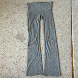 Grå yogapants från Gina Tricot Young avdelningen - Säljer ett par grå mjukisbyxor från Gina Tricot med sjusterbar midja/ du kan göra dem så lågmidjade du vill eller så högmidjade du vill och utsvängda ben. Byxorna är i mjukt och stretchigt material, perfekta för en avslappnad stil. De är lite korta på mig som 175cm.