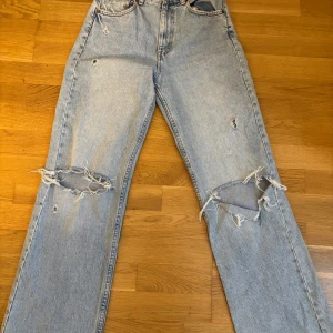 Ljusblå slitna jeans från Zara - Ljusblå jeans från Zara med flera slitningar och hål på benen. 