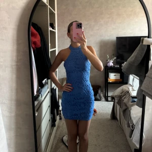 Blå spetsklänning med halterneck - Säljer en blå kortklänning med halterneck och öppen rygg. Klänningen har en figurnära passform. Från nakd.