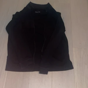 Svart jacka från Massimo Dutti - Snygg svart jacka från Massimo Dutti med dragkedja. Perfekt för en stilren look. Jackan har långa ärmar och en klassisk design. Använd mycket men funkar fortfarande perfekt