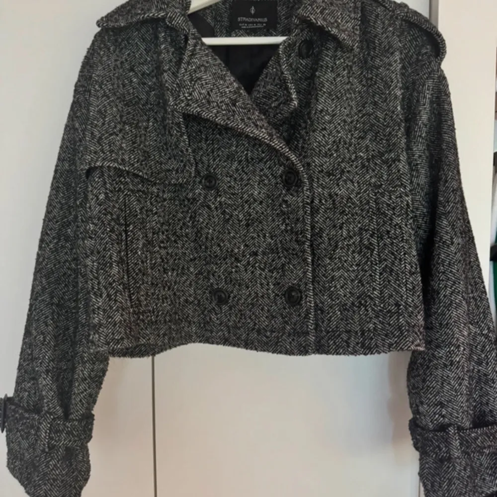 Säljer en snygg grå rutig kavaj från Stradivarius. Den är croppad med dubbelknäppning och har långa ärmar med knappar vid ärmsluten. Perfekt för en stilren look!. Takit.