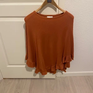 Orange stickad tröja från Isolde - Säljer en snygg orange stickad tröja från Isolde. Tröjan har långa ärmar och en volangdetalj vid nederkanten som ger en extra touch. Perfekt för att hålla sig varm och stilren under kyligare dagar.