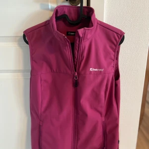 Rosa väst från TrekMates - Snygg rosa väst från TrekMates med dragkedja framtill. Perfekt för lager-på-lager under kyliga dagar. Västen har en hög krage och är ärmlös, vilket gör den idealisk för utomhusaktiviteter.