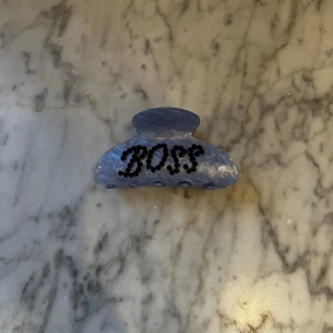 Blå hårklämma med text - Snygg blå hårklämma med texten 'Boss' i svarta bokstäver. Snygg både i håret och som extra detalj på outfiten! Oanvänd!