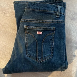 Mörkblå bootcut jeans från Miss Sixty - Snygga mörkblå bootcut jeans från Miss Sixty med klassisk femficksdesign. Jeansen har en diskret tvättad look och en logga på bakfickan. Perfekta för en avslappnad stil. 💞💞