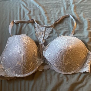 Grå spets-BH från Lindex - Säljer en elegant grå BH från Lindex med vacker spetsdetalj. Den har en smickrande passform och ett dekorativt mönster. Perfekt för att känna sig extra fin under kläderna. 💕