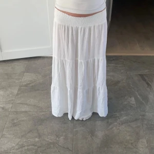 Vit långkjol - Säljer en vit långkjol med elastisk midja och flera lager som ger en fin volym. Perfekt för varma dagar och kan enkelt matchas med olika toppar. Pris kan diskuteras vid snabb affär.