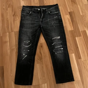 Nudie jeans med slitningar - Snygga svarta nudie jeans med slitningar och slim fit. Upplagda till L26. Original W32 L32. Pris kan diskuteras och ställ gärna frågor vid funderingar. 