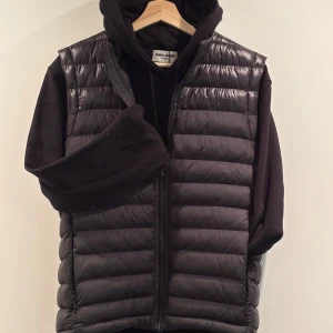 Svart dunväst från J.Lindeberg - Snygg svart dunväst från J.Lindeberg med dragkedja framtill. Perfekt för lager-på-lager och håller dig varm under kyliga dagar. Stilren design som passar till många olika outfits. Skick 10/10 Strl: M, passar också S ⭐️