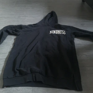 Svart oversized lång hoodie med texten 'Kindness' - Säljer en svart hoodie med texten 'Kindness' tryckt i vitt på bröstet. Tröjan har en klassisk design med huva och långa ärmar. Perfekt för en avslappnad stil eller när man bara vill mysa eller sova.🥰