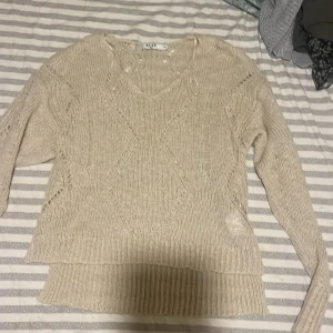 Beige stickad tröja från NA-KD - Säljer en snygg beige stickad tröja från NA-KD med v-ringning och ett fint stickat mönster. Tröjan har långa ärmar och ribbade kanter vid ärmslut och nederkant. Perfekt för kyliga dagar! Står xxs men passar även för storlek M då jag är en storlek M väldigt stor i sin storlek🍂