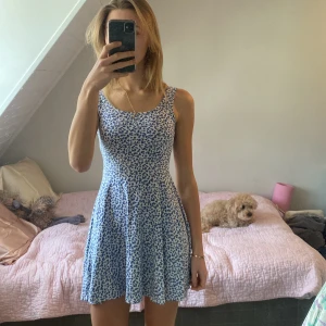 Blå blommig klänning från Don't Call Me Jennifer - Söt blå blommig klänning från Don't Call Me Jennifer. En kort klänningen med stretchit material och rund urigning. Super skön och oanvänd! Köpt i butik i Frankrike 