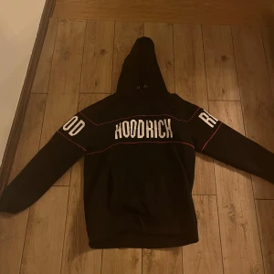 Svart tracksuit  från Hoodrich - Säljer en svart hoodie från Hoodrich med vit text på bröstet och ärmarna. Hoodien har en klassisk design med huva och långa ärmar. Perfekt för en avslappnad stil.