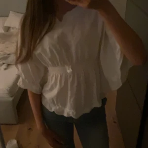 Vit blus med resårdetalj - Säljer en söt vit blus. Super osäker på vart den är från och vilken storlek den är i eftersom jag haft den ett bra tag, bara inte använt. Passar ivarfall mig som vanligtvis har storlek XS/XXS i tröjor och är 165 🥰