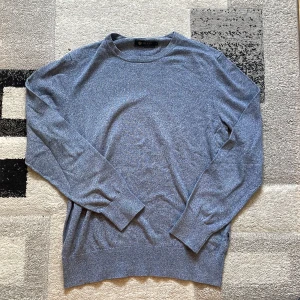 Blå stickad tröja från Riley - Snygg blåmelerad stickad tröja från Riley i storlek S. Tröjan har rund halsringning, långa ärmar och ribbade muddar. Perfekt för dig som gillar en klassisk och stilren look med en modern touch.