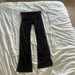 Svarta bootcut mjukisbyxor Gina Tricot - Svarta mjukisbyxor från Gina Tricot med bootcut-ben och låg midja. Byxorna är i mjukt och stretchigt material, perfekta för en chill och avslappnad look. Passformen är tajt men stretchig och de har en bred linning upptill.