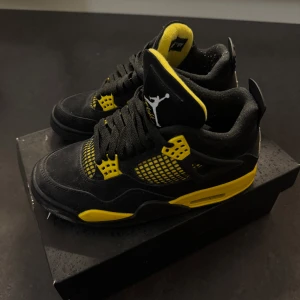 Nike Air Jordan 4 Retro svart/gul (thunder) - Nike Air Jordan 4 Retro i svart mocka med coola gula detaljer och meshpaneler. Skorna har klassisk Jumpman-logga på plösen och hälen, samt snörning och vadderad plös för extra komfort. Perfekta för dig som vill sticka ut med en ikonisk sneaker. Storlek 37,5 kvitto och original låda medföljer. Väldigt bra skick/nyskick, knappt använda. Köpt på SNS.